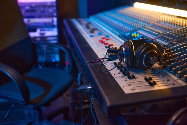 Primer plano de la mesa de mezclas de sonido con auriculares para productor musical en estudio