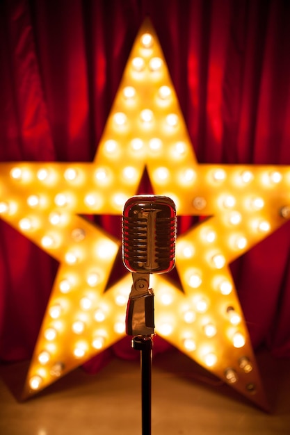 Foto primer plano del micrófono contra bombillas iluminadas en forma de estrella sobre el escenario