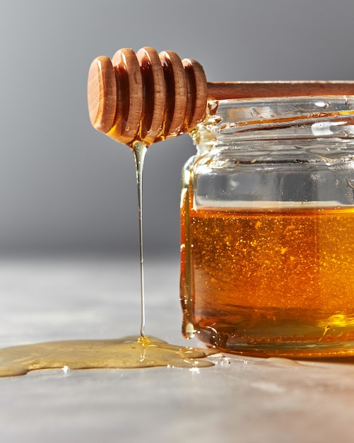 Primer plano de miel de flor dulce natural que gotea del palo sobre una mesa de piedra gris judío de rosh hashaná