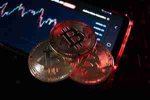 Foto primer plano de la moneda bitcoin con iluminación roja que alude a la caída de la moneda, profundidad de campo muy corta.