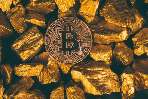 Primer plano de la moneda digital de bitcoin y pepita de oro o mineral de oro sobre fondo negro