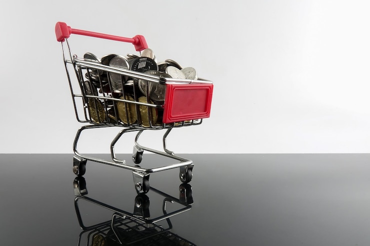 Foto primer plano de monedas en un carrito de compras en miniatura en una mesa de vidrio contra un fondo blanco
