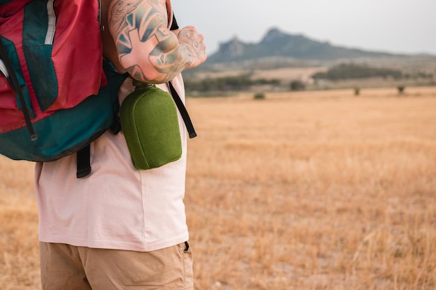 Primer plano de un montañero tatuado con una cantimplora y una mochila