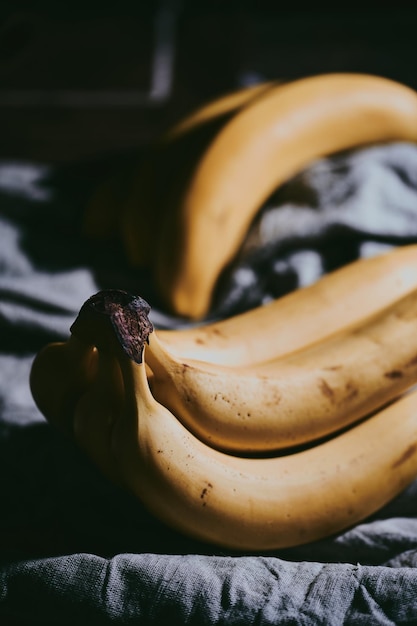 Foto un primer plano de un montón de plátanos sobre un fondo de tela oscura.