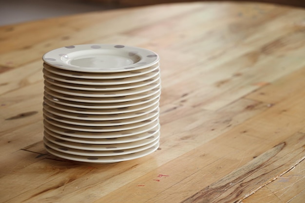 Primer plano de un montón de platos de pie sobre una mesa de madera Preparándose para la fiesta