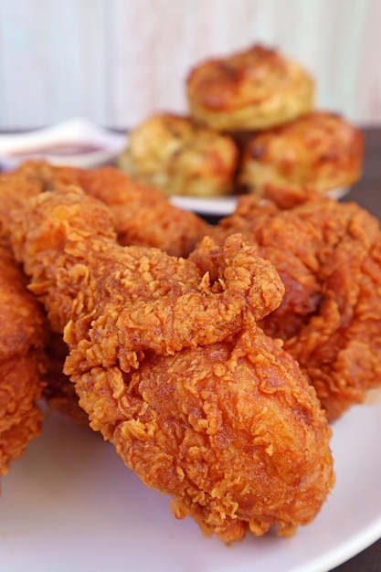 Primer plano montón de pollos fritos crujientes de color marrón dorado con galletas borrosas en segundo plano.