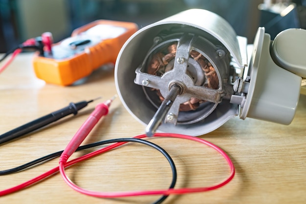 El primer plano del motor de hierro del ventilador de refrigeración doméstico se encuentra sobre una mesa en reparación