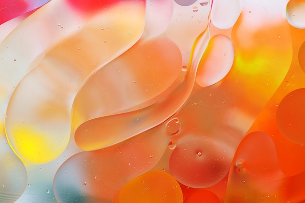 Primer plano del movimiento de las gotas de aceite en la superficie del agua. Fondo macro abstracto colorido de gotas de aceite sobre la superficie del agua.