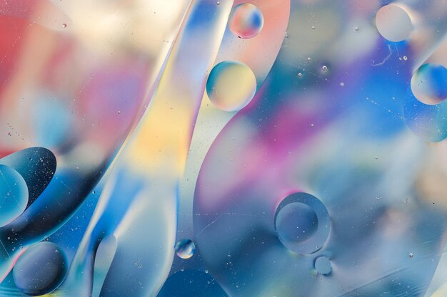 Primer plano del movimiento de las gotas de aceite en la superficie del agua. Fondo macro abstracto colorido de gotas de aceite sobre la superficie del agua.