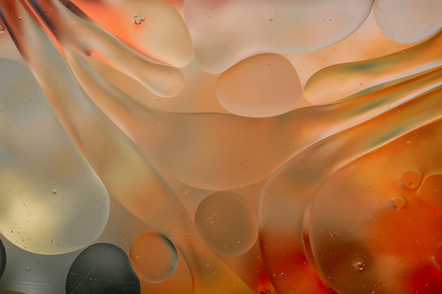 Primer plano del movimiento de las gotas de aceite en la superficie del agua. Fondo macro abstracto colorido de gotas de aceite sobre la superficie del agua.