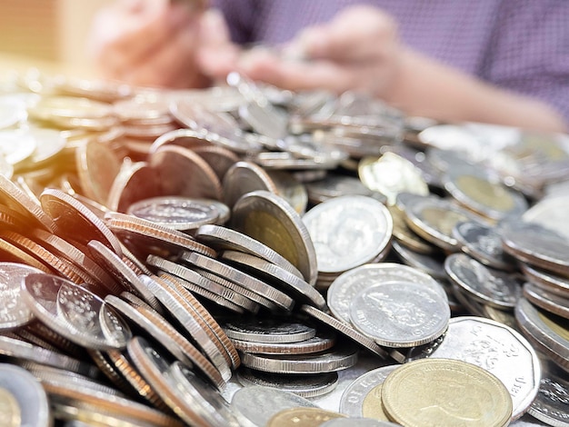 Primer plano de muchas monedas tailandesas con luz y desenfoque de solf de manos