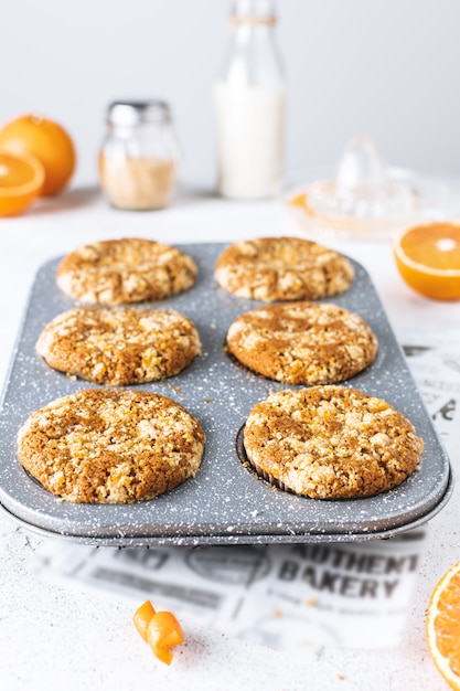 Primer plano de muffins de naranja en una sartén con streusel