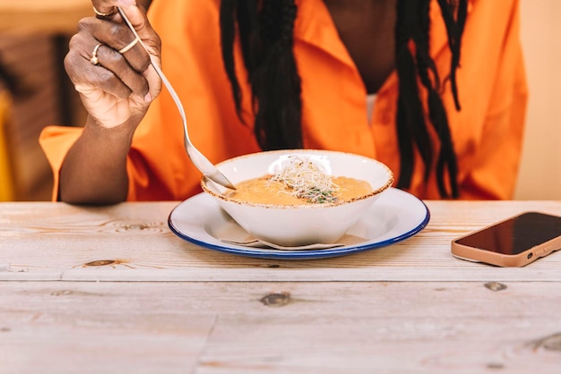 Primer plano de una mujer afroamericana comiendo una sopa de crema de verduras saludables Concepto de comida saludable