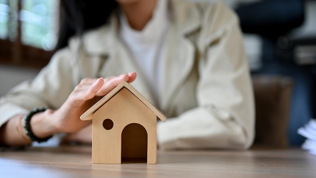 Foto primer plano una mujer agente de bienes raíces o corredor de seguros de hogar tocando el modelo de techo de una casa