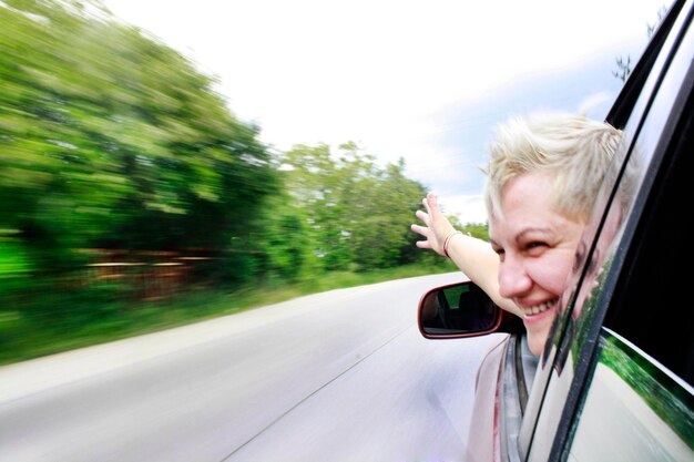 Foto primer plano de una mujer alegre mirando por la ventana del coche