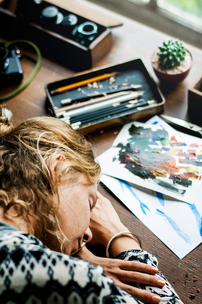 Foto primer plano de la mujer artista tomando una siesta en la mesa de trabajo