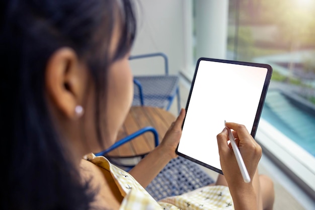 Primer plano Mujer asiática manos sosteniendo y señalando con lápiz en tableta Trazado de recorte en pantalla blanca aislado Comunicación de tecnología social de compras en línea