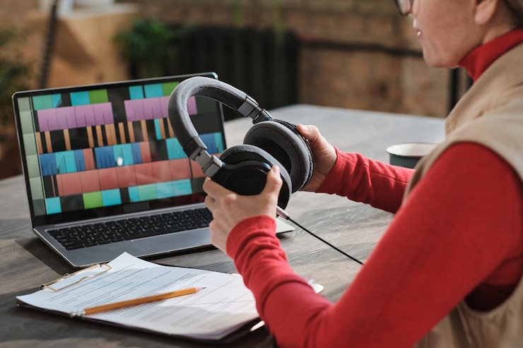 Foto primer plano de mujer en auriculares sentado en la mesa con portátil y grabación de podcast para programa en línea en estudio de radio