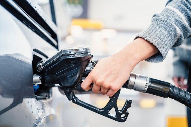 Primer plano de una mujer bombeando combustible de gasolina en un coche en una gasolinera Gasolina o gasolina que se bombea a un motor Concepto de transporte