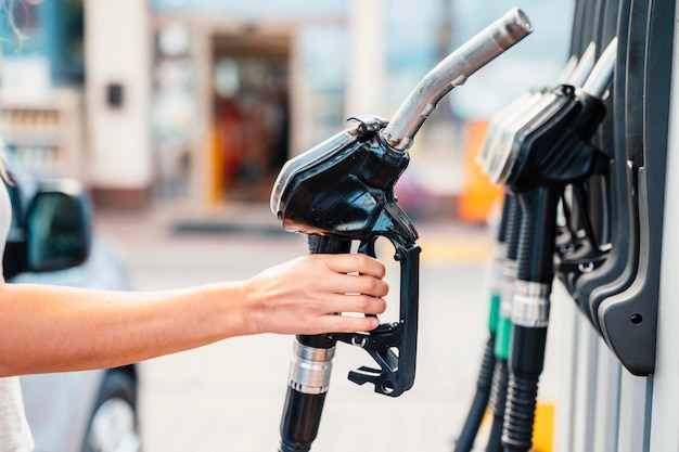 Primer plano de una mujer bombeando combustible de gasolina en un coche en una gasolinera Gasolina o gasolina que se bombea a un motor Concepto de transporte