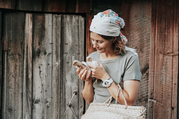 Primer plano de una mujer campesina sosteniendo pollo pequeño