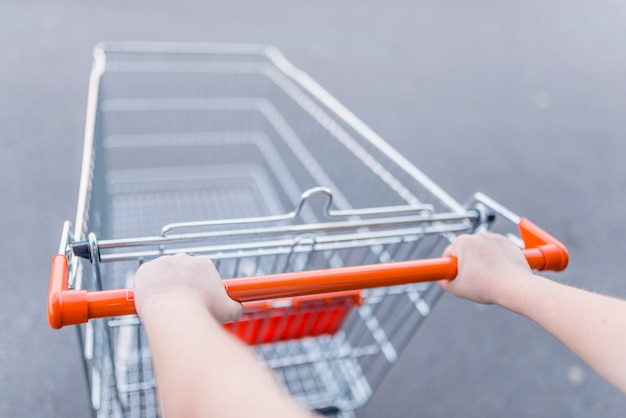 Primer plano de mujer con carrito de compras. mujer empujando carrito de compras en el supermercado