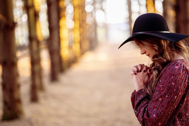 Primer plano de una mujer caucásica, que reza en el bosque otoñal