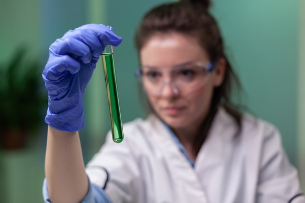 Primer plano de una mujer científica mirando el tubo de ensayo con muestra de adn examinando el experimento de microbiología