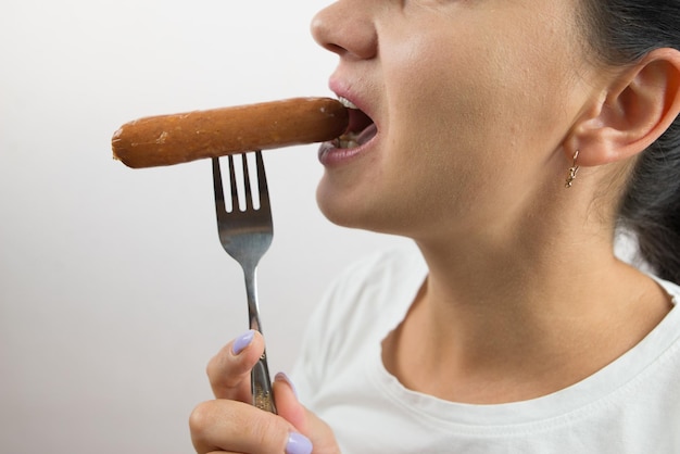 Primer plano de una mujer comiendo una salchicha