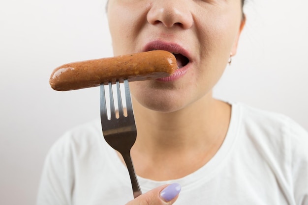 Primer plano de una mujer comiendo una salchicha