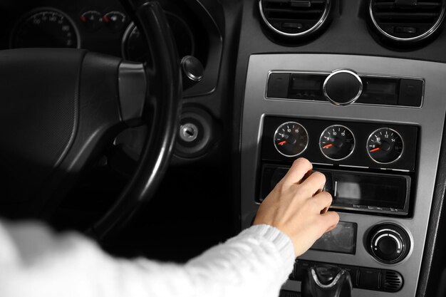 Primer plano de una mujer conduciendo un coche y sintonizando la radio