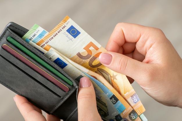 Foto primer plano de una mujer contando billetes en euros en su monedero dinero en euros en la cartera de una persona que paga algo en efectivo