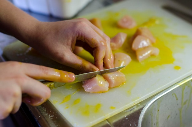 Primer plano de una mujer cortando carne en la tabla de cortar