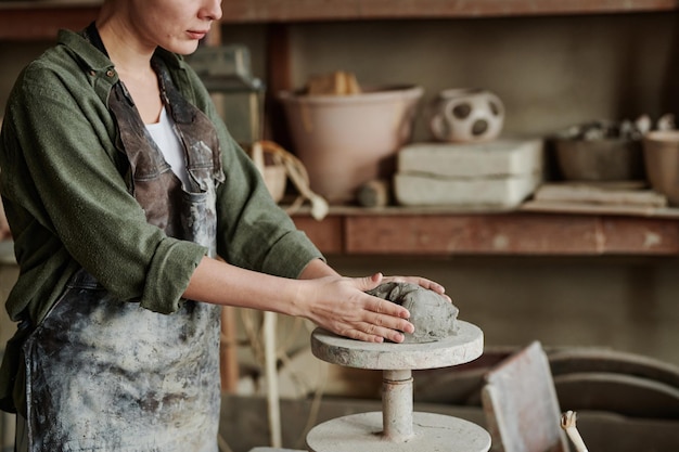 Primer plano de una mujer en delantal trabajando con arcilla y haciendo diferentes esculturas en el taller