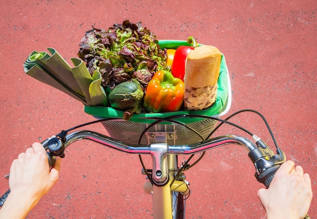 Primer plano de una mujer deportiva con comestibles en una bicicleta de cesta en un día soleado de verano