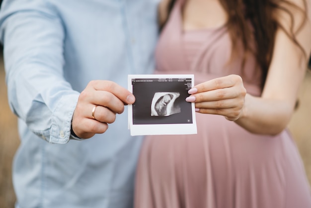 Foto primer plano de una mujer embarazada irreconocible con imagen de ultrasonido en la mano