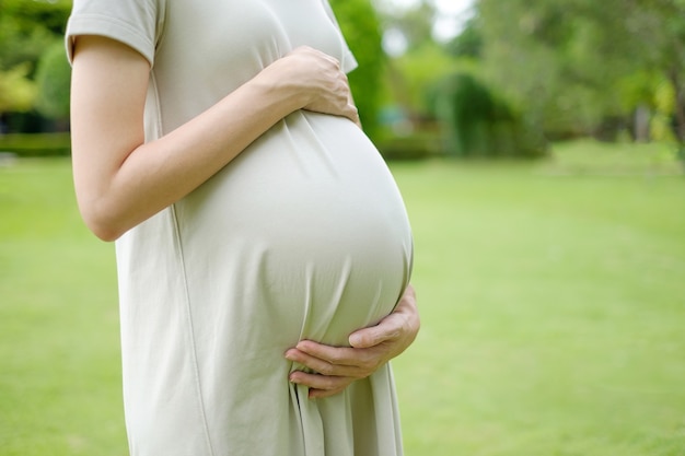 Primer plano de mujer embarazada con un vestido largo en colores pastel