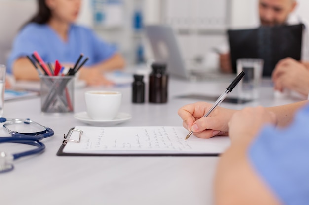 Primer plano de una mujer enfermera mano analizando examen médico escribiendo tratamiento de enfermedad