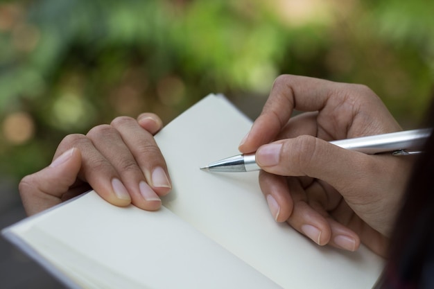 Primer plano de una mujer escribiendo en un diario con una pluma
