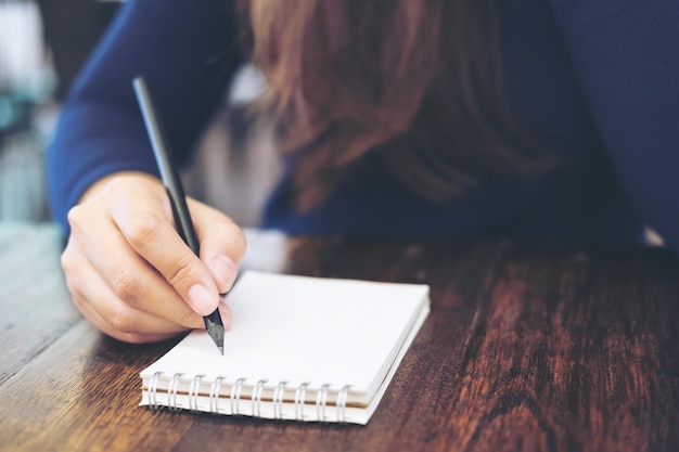 Foto primer plano de una mujer escribiendo en un libro en la mesa