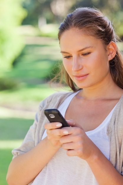 Primer plano de mujer escribiendo un mensaje de texto en el parque