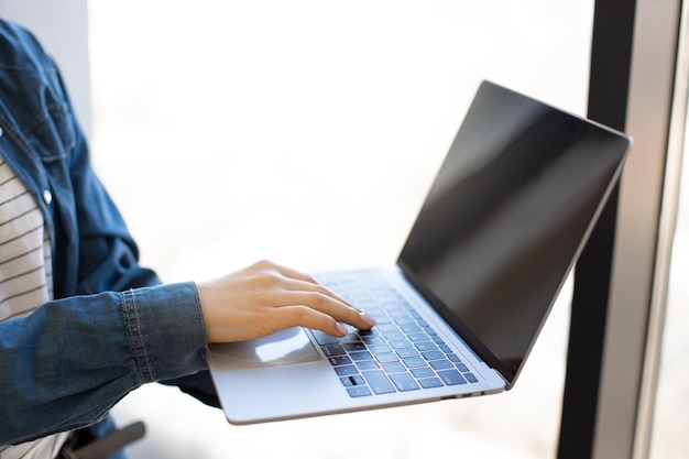 Primer plano de mujer escribiendo en el teclado de la computadora portátil inalámbrica