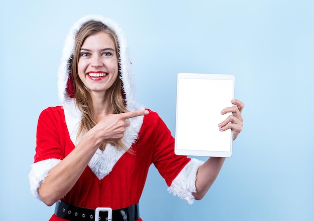 El primer plano de una mujer feliz caucásica con ropa de santa apuntando a la tableta digital