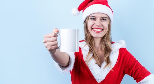 Primer plano de una mujer feliz caucásica con ropa de santa sosteniendo una taza blanca