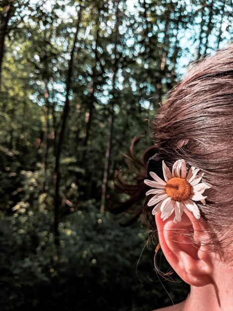 Foto primer plano de una mujer con una flor en el bosque