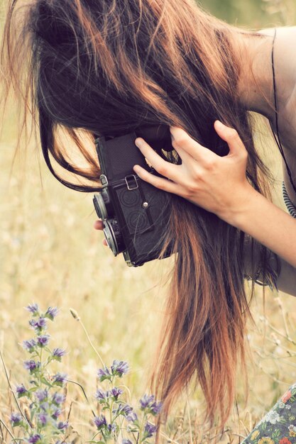 Foto primer plano de una mujer fotografiando flores en el campo