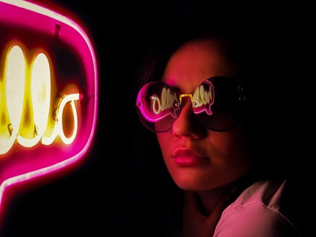 Foto primer plano de una mujer con gafas de sol contra un fondo negro