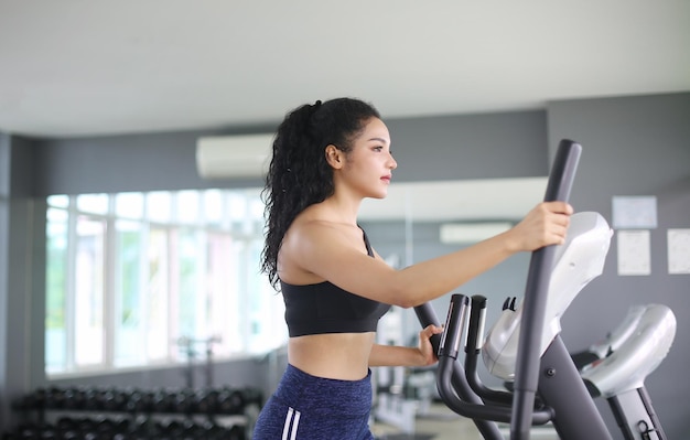 Primer plano de una mujer haciendo ejercicio en una máquina elíptica en el gimnasio