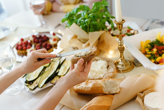 Primer plano de una mujer haciendo un sándwich de queso crema en la mesa festiva