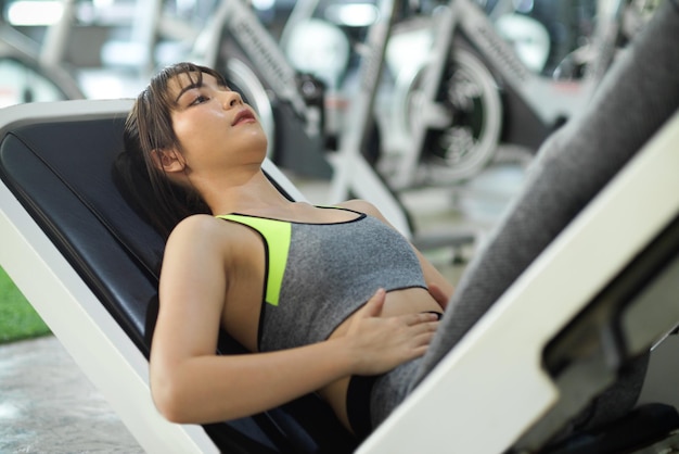 Primer plano, mujer hermosa fitness usando una máquina de prensa en un gimnasio. mujer ejercitando las piernas en una máquina.